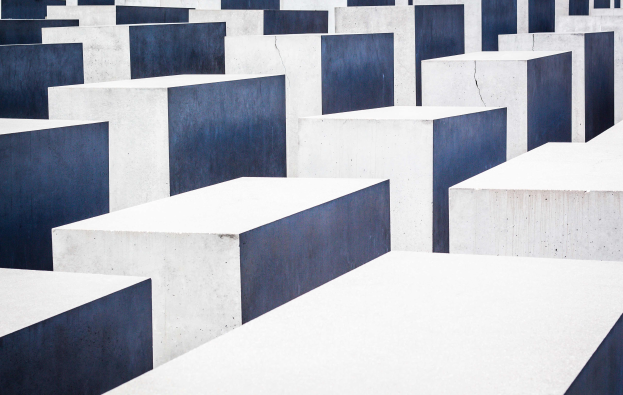 Ein Feld rechteckiger Betonplatten in verschiedenen Höhen, die in einem Gittermuster angeordnet sind, bekannt als das Holocaust-Mahnmal für die ermordeten Juden Europas, befindet sich in Berlin, Deutschland.