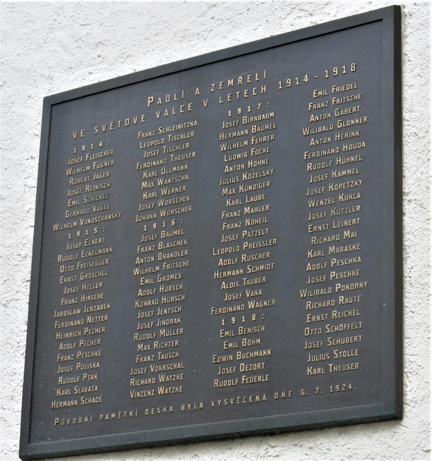 Plakette an einer Gebäudewand mit der Inschrift "Plakette für die Opfer des Holocaust" in dunklem Material mit einem dekorativen Rahmen.