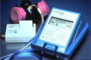 Gasmaske auf einem Tisch neben einem Gasdetektorgerät mit einem angeschlossenen Kabel.