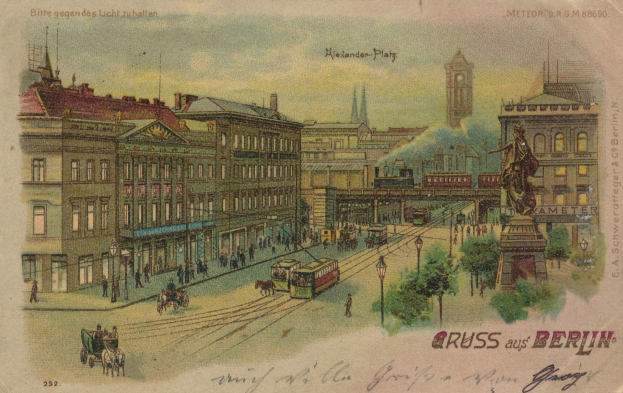 Schwarz-weiß-Postkarte einer belebten Berliner Straße mit frühen 20. Jahrhundert-Gebäuden, horse-drawn carts, motor vehicles, pedestrians, street lamps, trees, a statue on a pedestal, and cloudy sky.