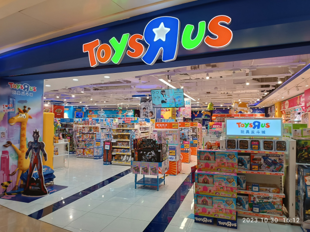 Ein Toys R Us Geschäft in einem Einkaufszentrum mit Regalen voller Spielzeug, Deckenbeleuchtung, einem Geschäftsschild und einem Wasserzeichen in der rechten unteren Ecke.