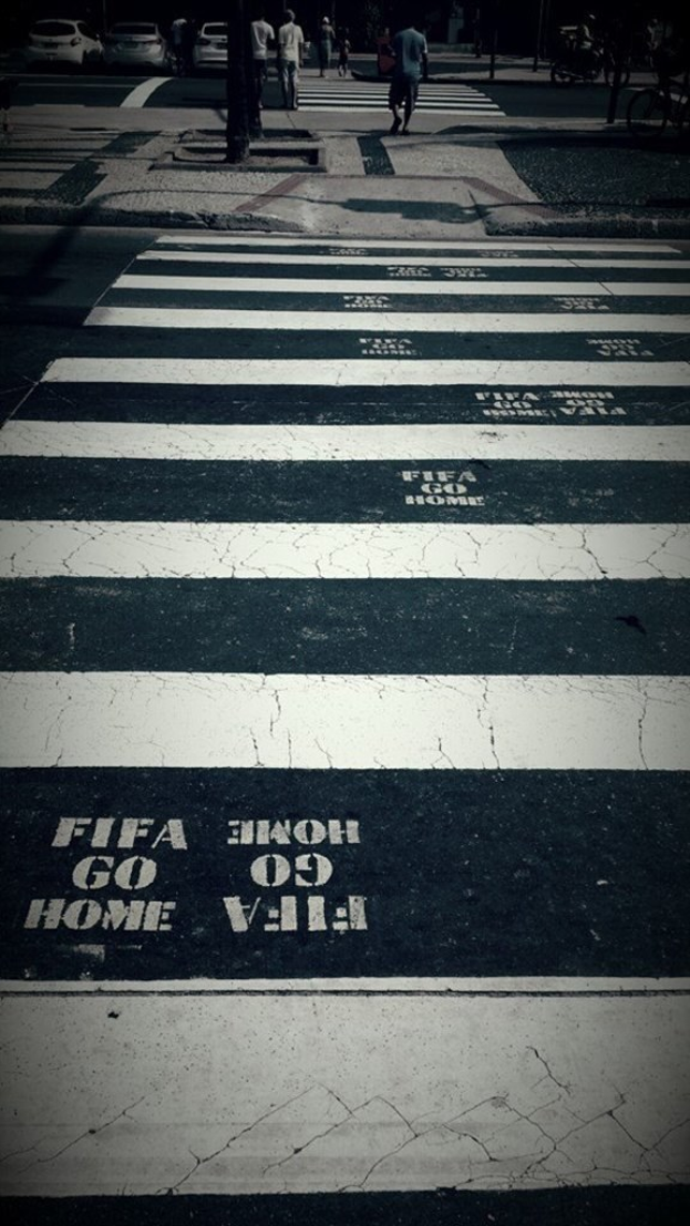 Menschen auf einem Zebrastreifen mit sichtbaren Autos im linken oberen Eck.