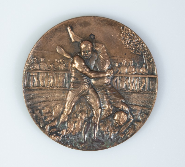 Eine Bronzemedaille mit einem Mann beim Golfspielen auf einem weißen Hintergrund.