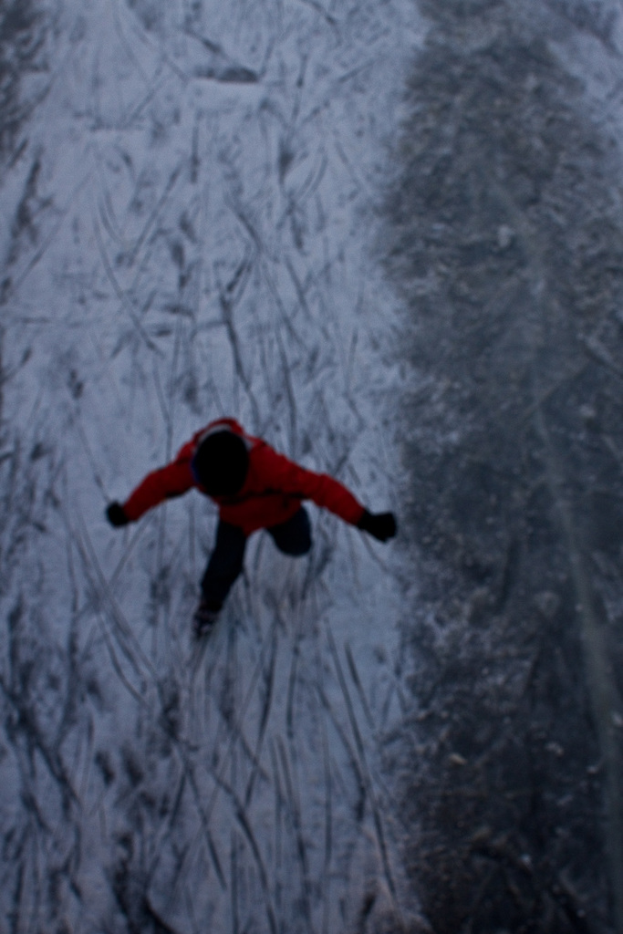 Eine Person in roter Jacke und schwarzer Mütze läuft auf Schnee.