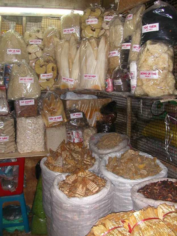 Ein Marktstand mit ordentlich sortierten Lebensmitteln in Tüten und Plastikhauben, einschließlich weiterer Gegenstände, die auf einen gut sortierten und organisierten Laden hinweisen.