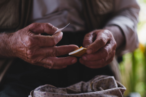 Alter Mann hält ein Blatt Papier in den Händen und sieht besorgt aus, mit unscharfem Hintergrund.