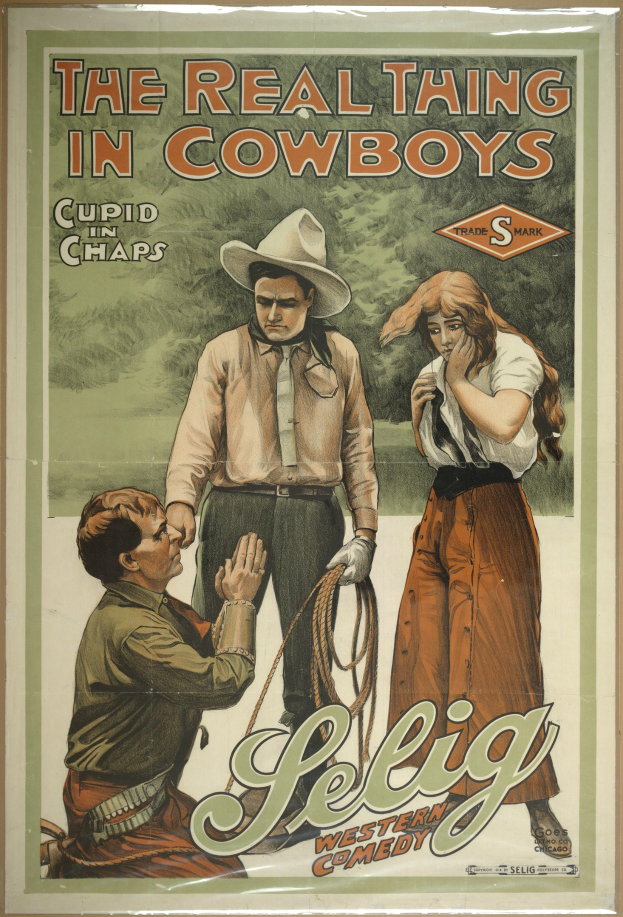 Plakat an einer Wand mit drei Personen – einem Mann mit Cowboyhut, einem anderen Mann mit Cowboyhut und einer Frau in einem langen Kleid – mit der Aufschrift "Das echte Ding bei Cowboys" in fetter schwarzer Schrift auf einem hellgelben Hintergrund.