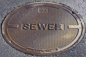 Metall-Schachtobjekt auf der Straße mit dem Wort "Kanal" geprägt