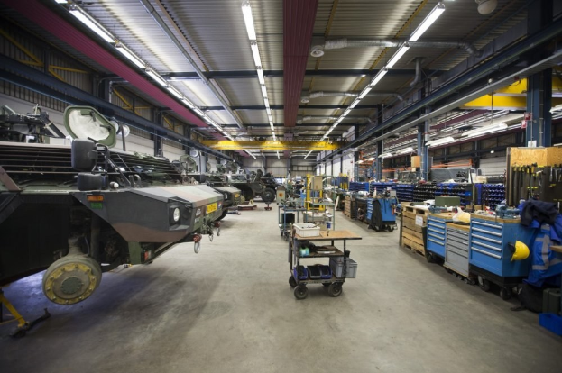 Ein gro\sser Lagerraum voller Maschinen, darunter Fahrzeuge auf der linken Seite, Wagen mit Gegenst"anden, h"olzerne Kisten und andere Gegenst"ande auf der rechten Seite sowie Lichter oben.