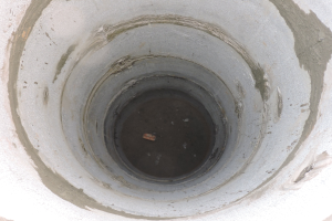 Betonrohr mit mittigem kreisförmigen Durchbruch und einem Gegenstand darin, umgeben von einer Betonwand.