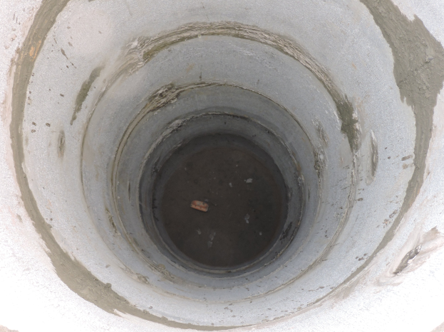 Betonrohr mit mittigem kreisförmigen Durchbruch und einem Gegenstand darin, umgeben von einer Betonwand.