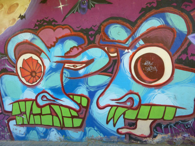 Ein leuchtendes, farbenfrohes Graffiti-Mural an der Seite eines Gebäudes mit verschiedenen Formen und Farbtönen.