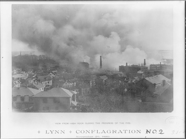 Ein Schwarz-Weiß-Foto einer Stadtlandschaft mit Rauch, der aus Gebäuden, Bäumen und dem Himmel aufsteigt, mit dem Text "Lynn und Conflagration No. 2" unten.