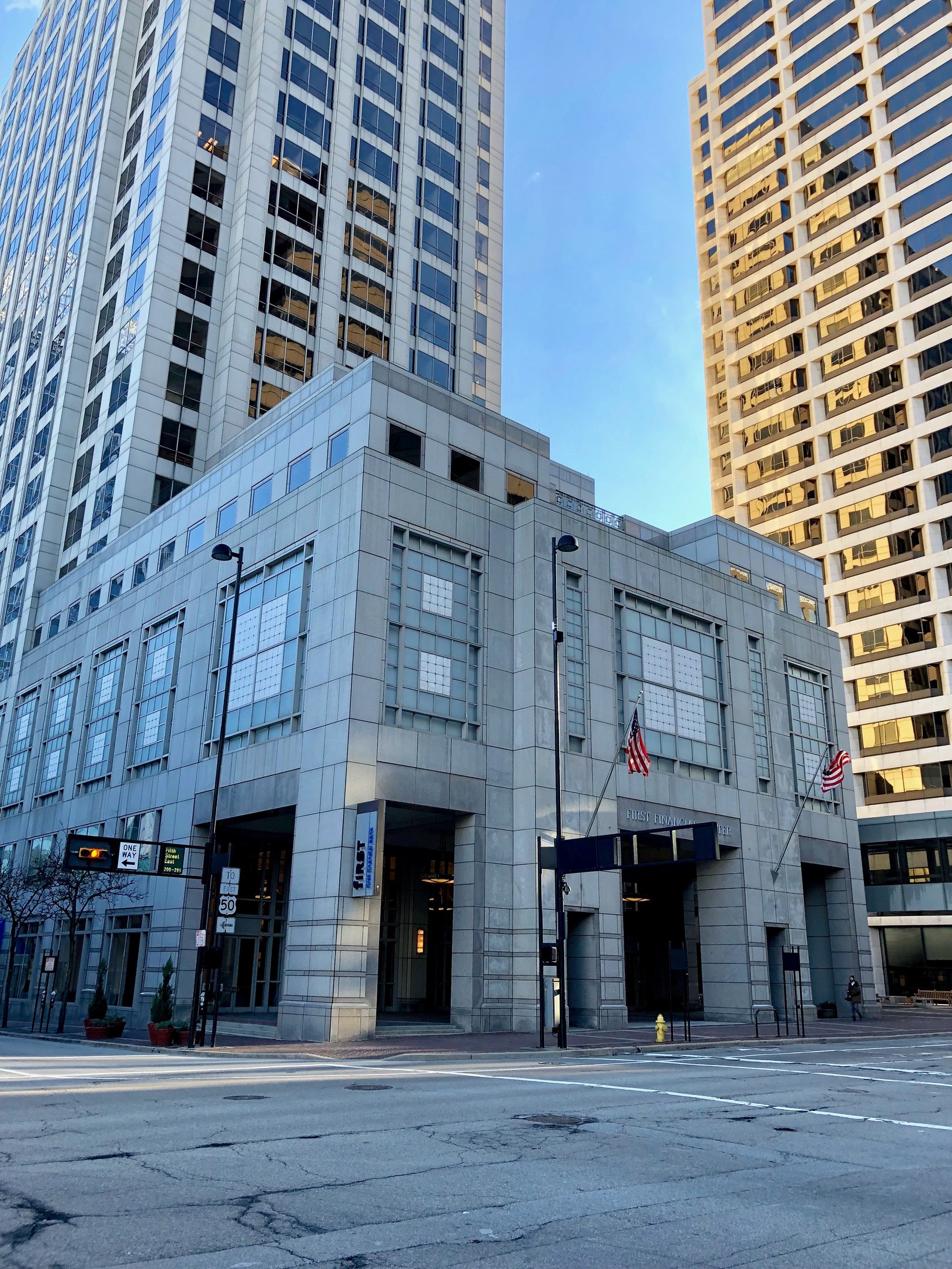 Großes Gebäude mit vielen Fenstern, identifiziert als Hauptquartier der Chicago Public Library, umgeben von städtischen Straßen-Elementen wie Pfosten, Verkehrszeichen, Schildern, Bäumen und einem bewölkten Himmel.