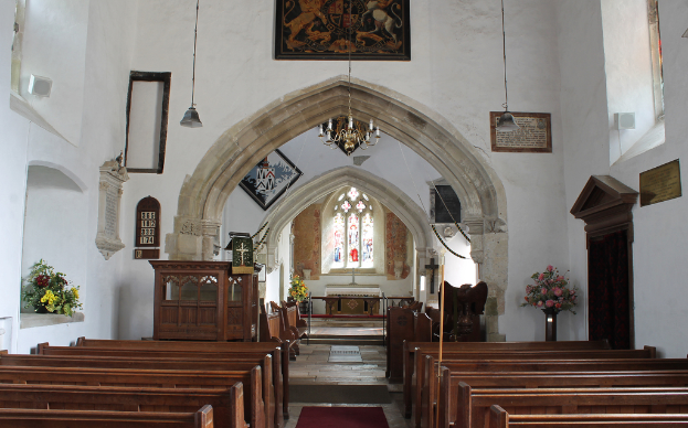 Eine Kircheninnenansicht mit Blumenvasen, Bänken, Fotorahmen und Lichtern.