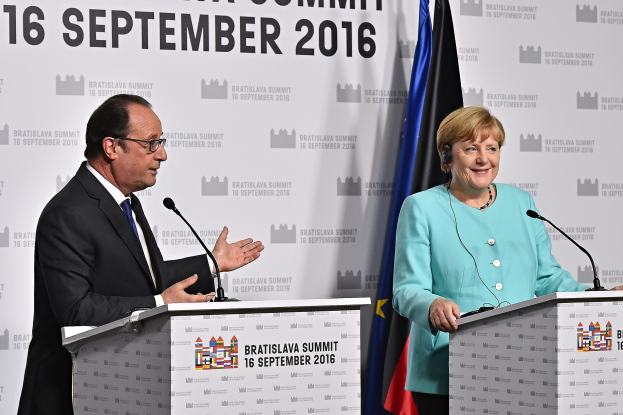Bundeskanzlerin Angela Merkel und Frankreichs Präsident François Hollande stehen vor zwei Podien mit Mikrofonen, beide lächeln, mit einem Banner im Hintergrund, auf dem 'Bratislava Gipfel 2016' steht.