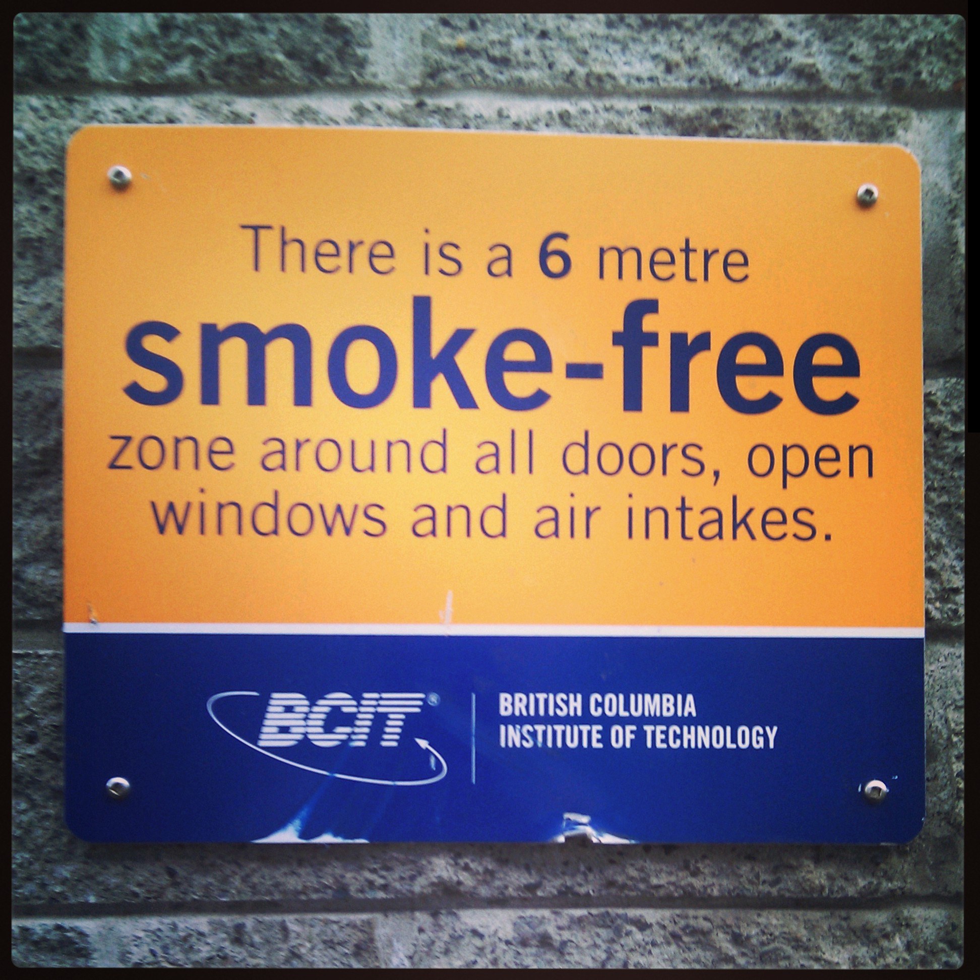 Ein Schild an einer Wand, das eine 6 Meter rauchfreie Zone um Türen, offene Fenster und Luftansaugöffnungen anzeigt.