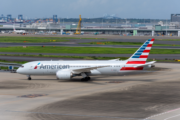 American Airlines-Flugzeug auf der Rollbahn eines Flughafens mit umliegender Infrastruktur und wolkenlosem Himmel.