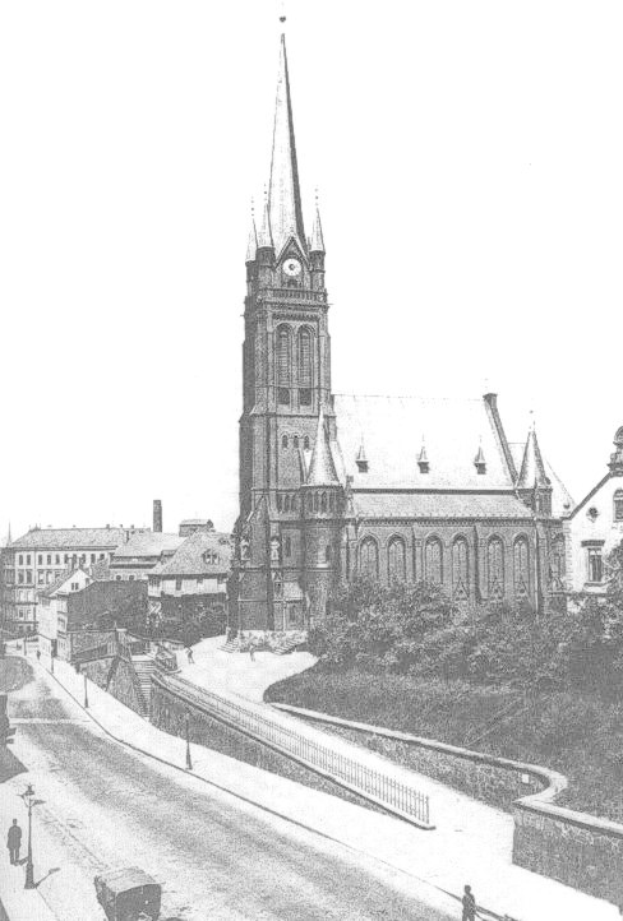Schwarzes und weißes Foto einer Stadtstraße mit St. Peter's Church im Hintergrund, gesäumt von Gebäuden, Bäumen, Fahrzeugen und Passanten.