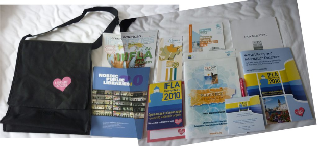 Eine Tasche mit "Bibliotheksliebhaber" drauf und einige Bücher auf einem Bett.