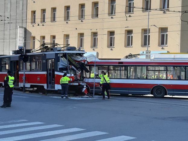 Rote und weiße Straßenbahn krachte an der Seite der Straße mit ein paar Menschen in der Nähe und einem Gebäude im Hintergrund.