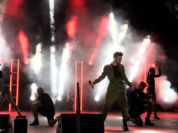 Drake performs auf der Bühne beim Coachella Valley Music and Arts Festival 2018, ein Mikrofon haltend, umgeben von tanzenden Menschen in einer Hockstellung, mit einem Kameramann, Lautsprechern und Deckenleuchten im Hintergrund.