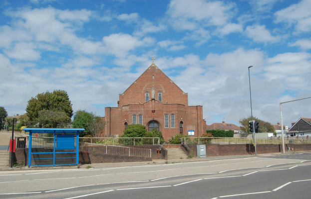 Eine Straße mit einem blauen Unterstand, Geländern, Stufen, Laternen, Verkehrsampeln, Bäumen, Gebäuden mit Fenstern und einem bewölkten Himmel, mit einer Kirche in der Mitte.