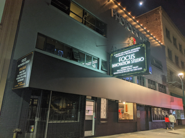 Außenansicht des Focus Innovation Studio in New York City bei Nacht, mit beleuchteten Fenstern, Namensschildern und Passanten auf dem Gehweg unter Straßenbeleuchtung.