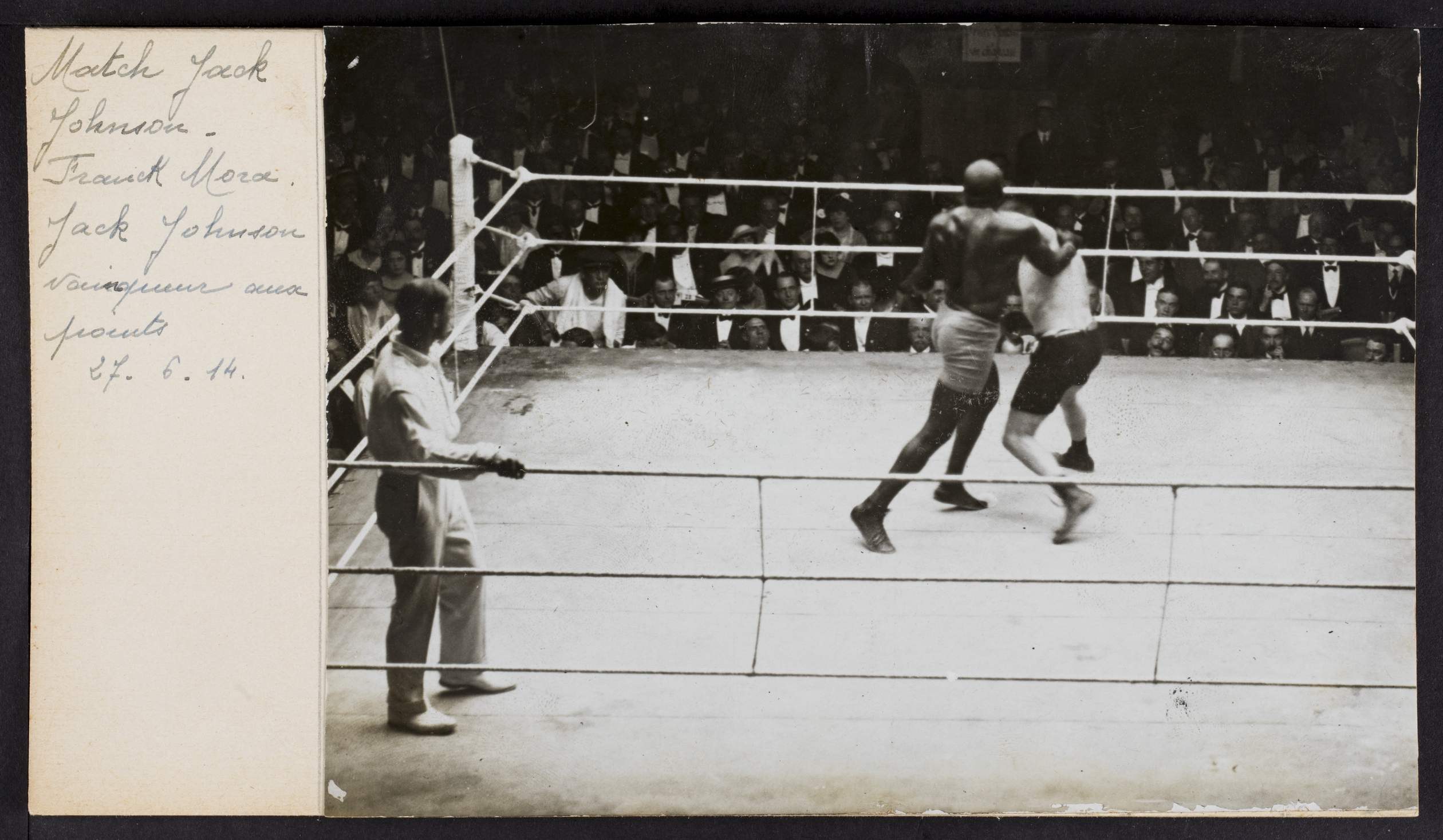 Schwarzes und weißes Foto von zwei Boxern in einem Ring mit einem Schiedsrichter links und Zuschauern im Hintergrund, betitelt mit "Jack Johnson vs Frank Morgan".