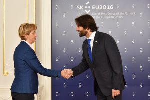 Bundeskanzlerin Angela Merkel und Joachim Gauck bei einem EU-Gipfeltreffen, die sich freundlich die Hände schütteln und vor einem Banner und einer Tür stehen.