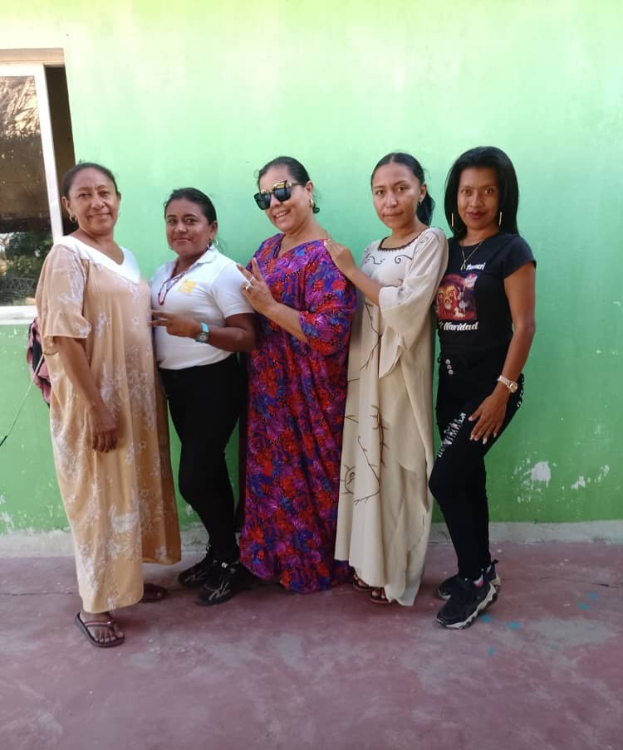Gruppe von Frauen vor einer grünen Wand mit einem Fenster auf der linken Seite bei einem International Women's Day-Event