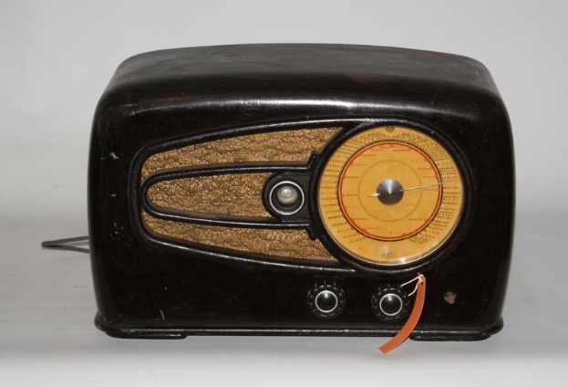 Ein altmodisches schwarzes und braunes Radio mit einem schwarzen Gehäuse und braunen Akzenten steht auf einem weißen Tisch.