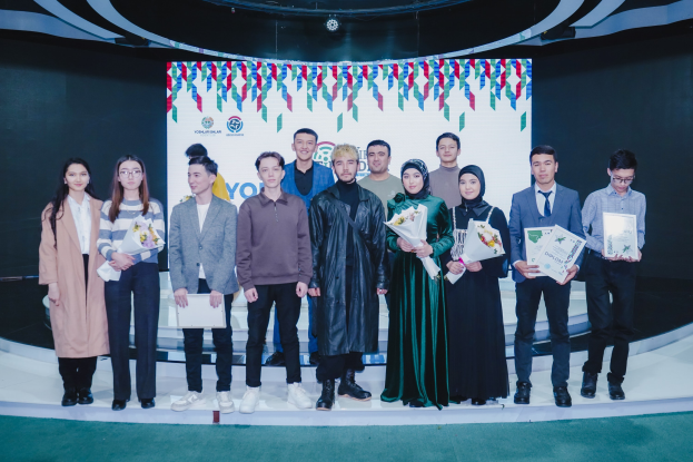 Gruppe von Menschen auf einer Bühne mit Blumensträußen und Zertifikaten, mit einem "Jugend-Solar-Awards 2019"-Hintergrund.